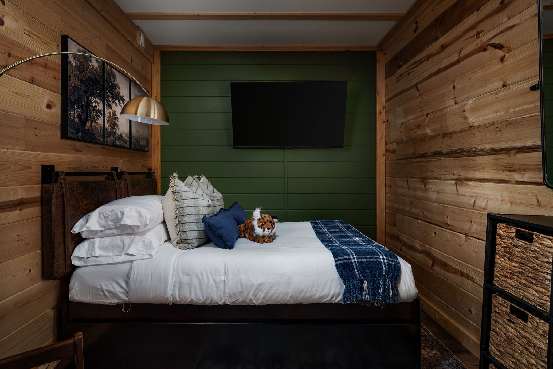 Guest bedroom with a forest green feature wall, crisp white bedding and a navy plaid throw
