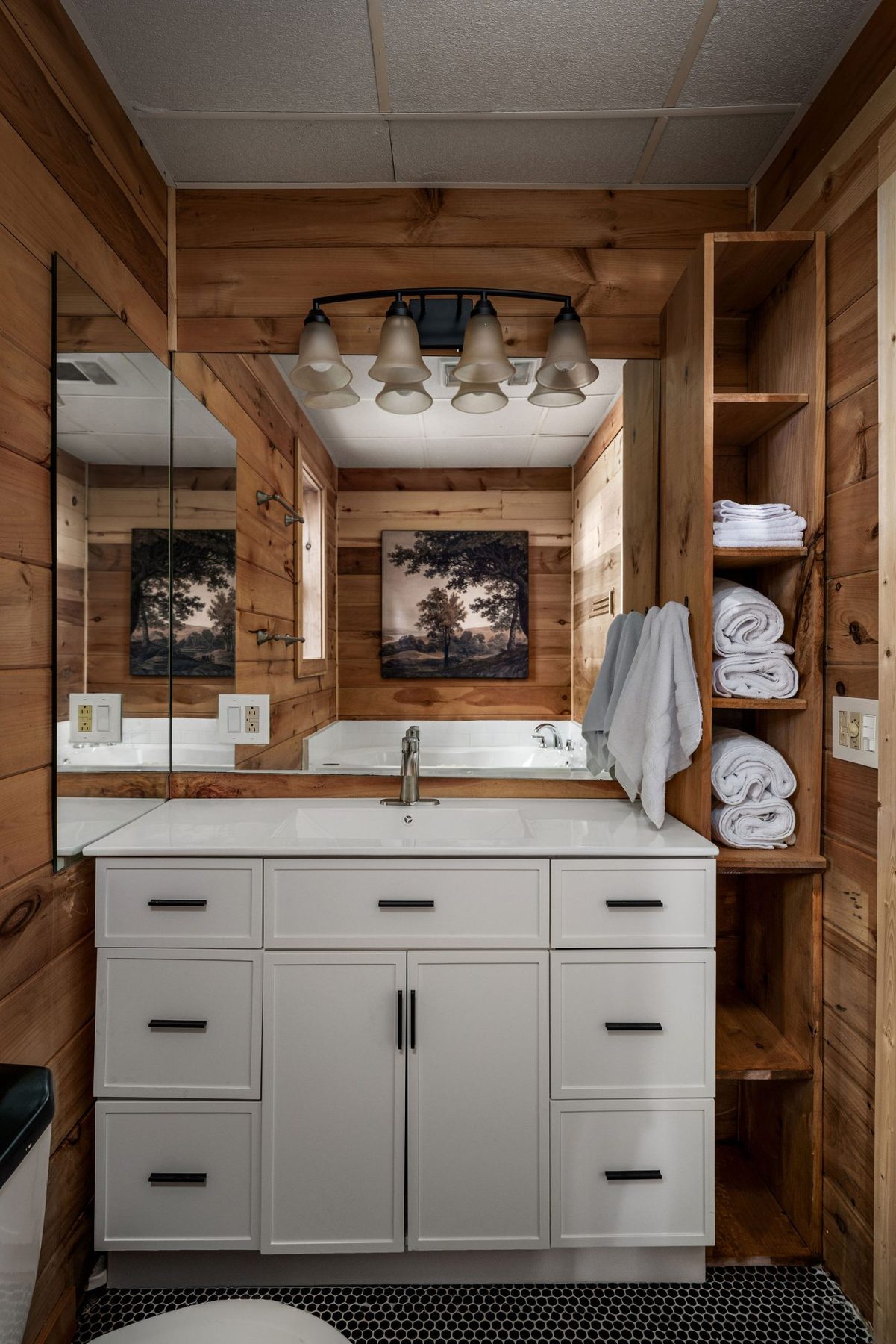 Bathroom with a white vanity, black framed mirror and open towel shelving