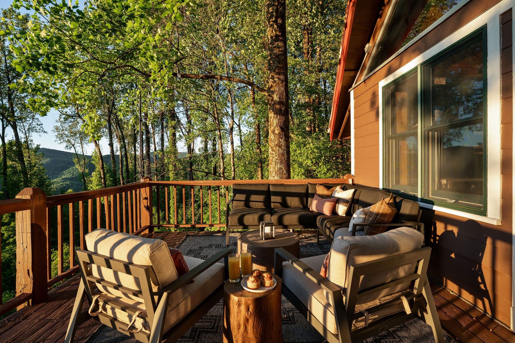 Upper deck lounge with outdoor sofas, plaid cushions and a forest canopy