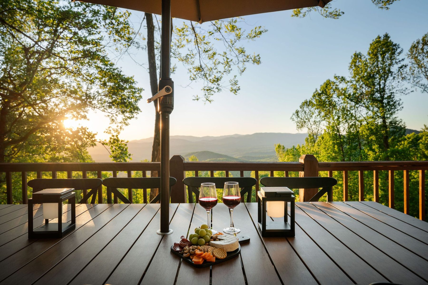 Deck dining table set for sunset, with lanterns and wine overlooking the ridge
