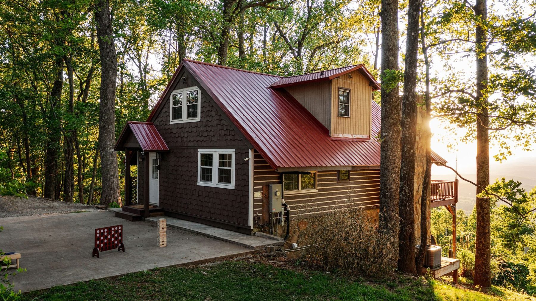 Exterior of the cabin in the woods: shingle siding, red metal roof and wraparound deck
