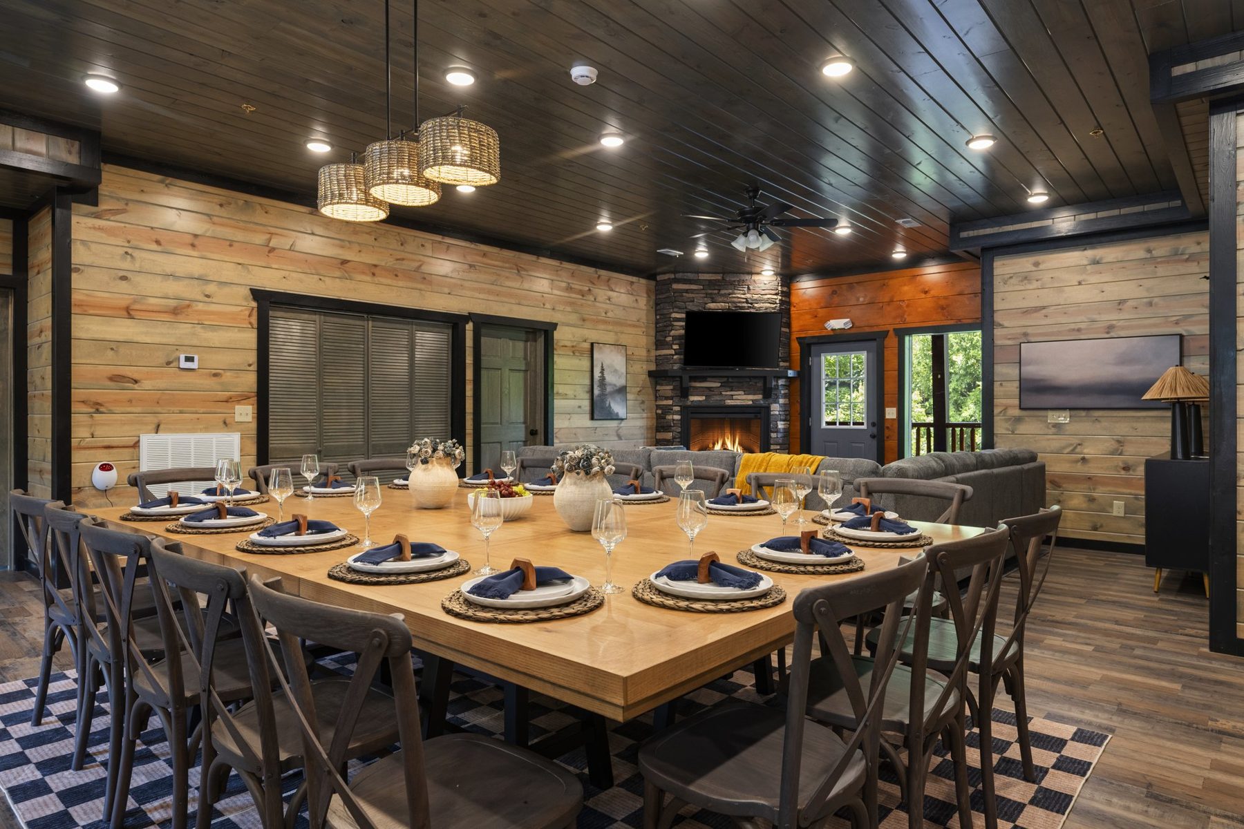 Long farmhouse dining table with cross-back chairs, woven pendants and navy napkins