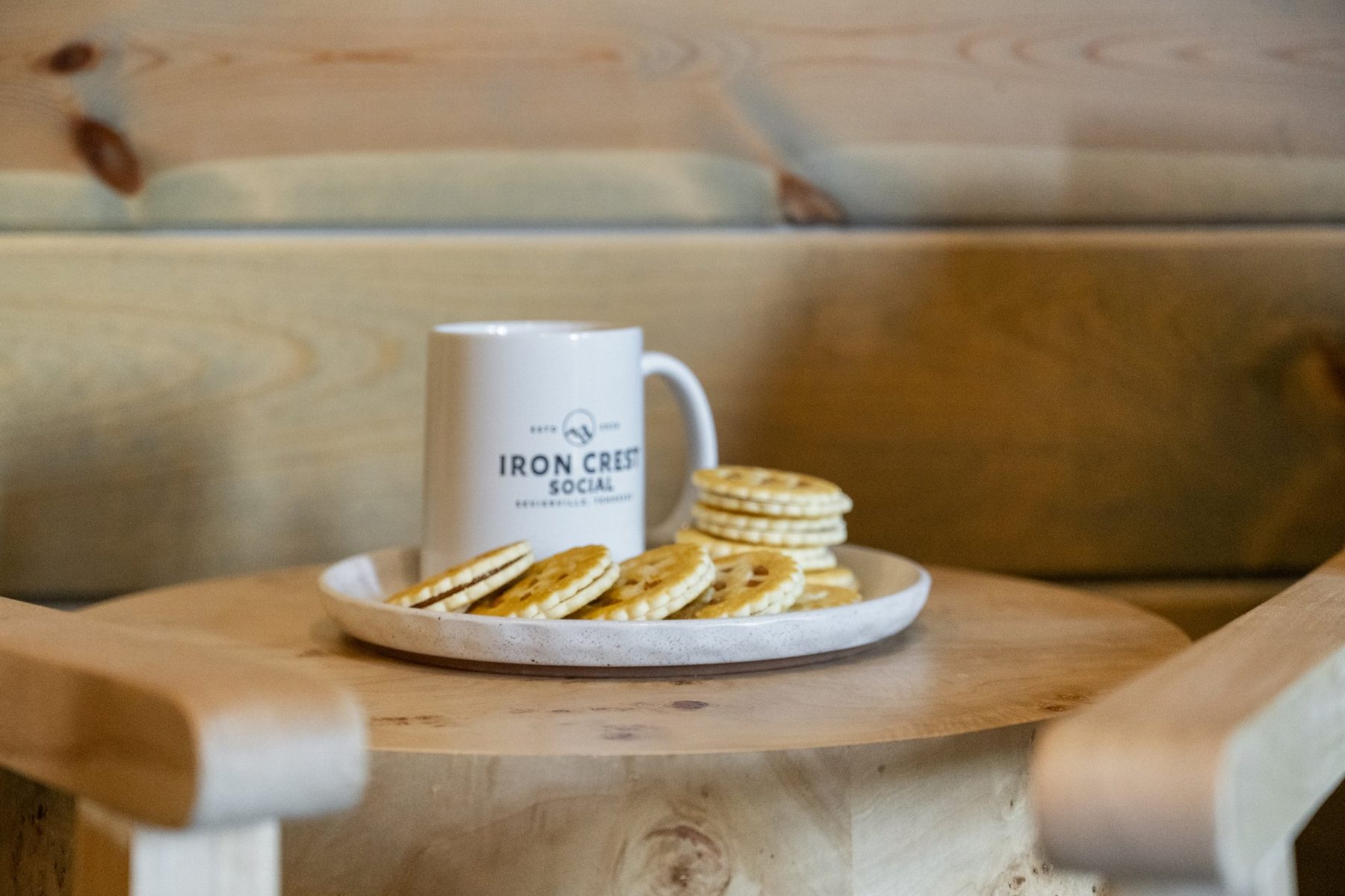 Branded Iron Crest Social mug with biscuits on a burl side table