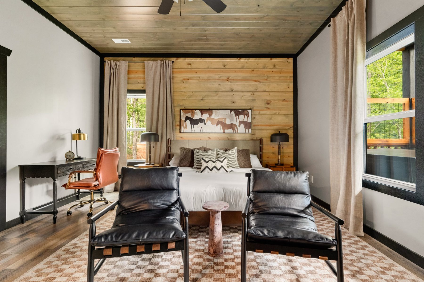 Bedroom with black leather lounge chairs, a horse-print headboard wall and a checked rug