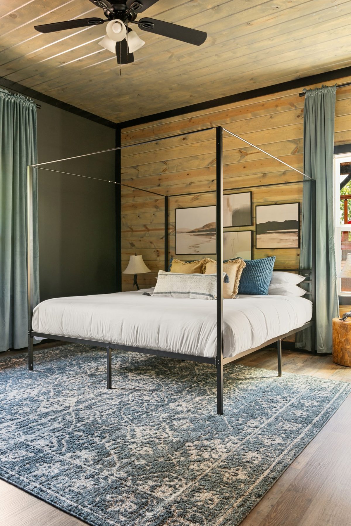 Four-poster bedroom with sage curtains and a blue vintage rug
