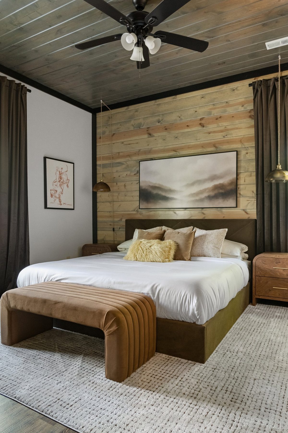 Pine-clad bedroom with a channel-tufted bench and landscape artwork