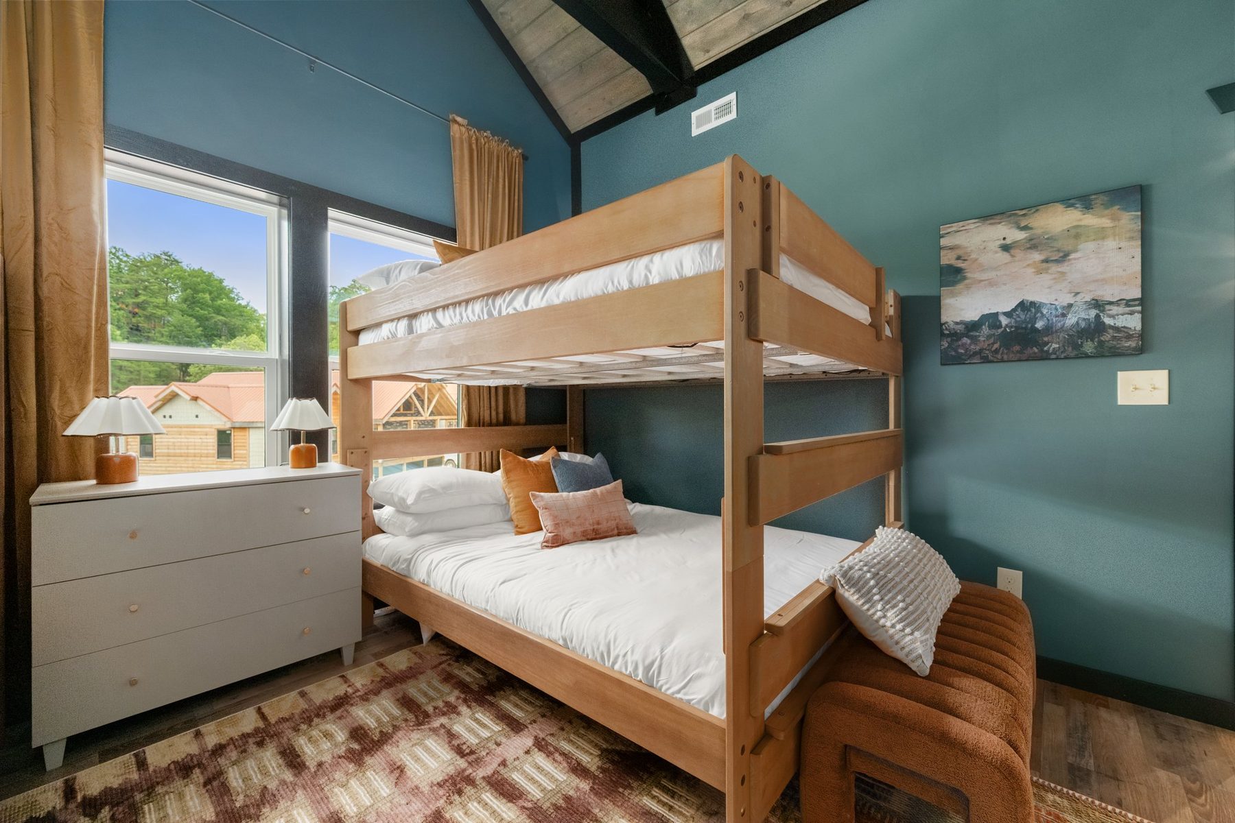 Bunk room with teal walls, timber bunks and a patterned rug