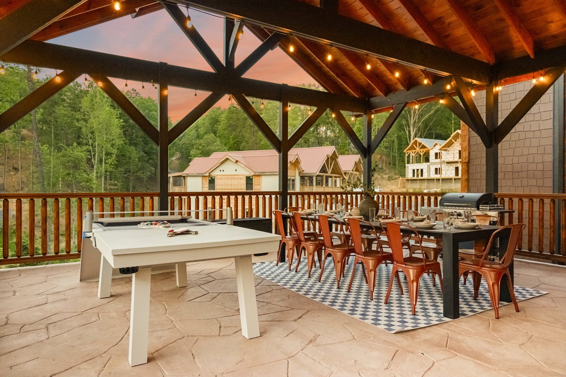 Pavilion deck at sunset with a ping-pong table, dining for twelve and festoon lights