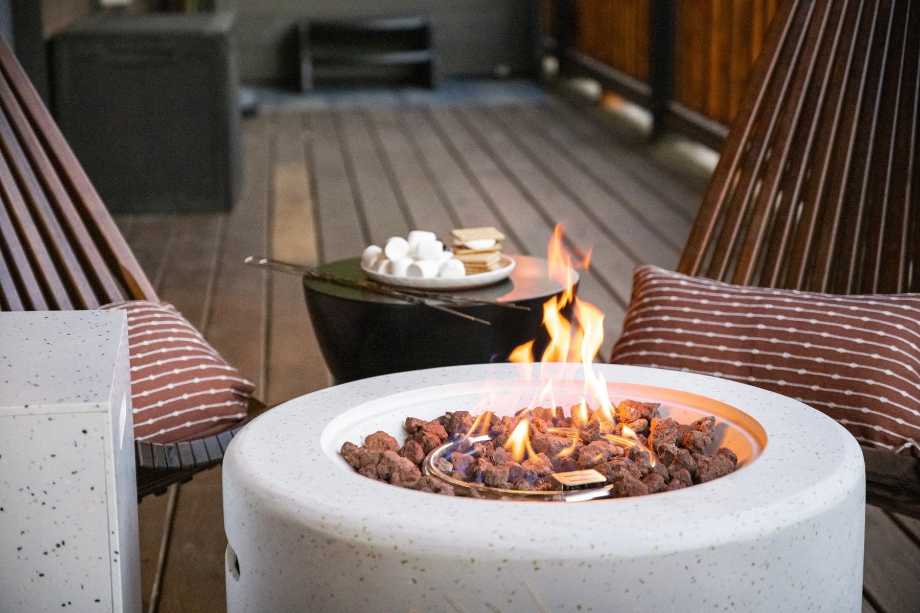 Fire table with s'mores and striped cushions on the deck