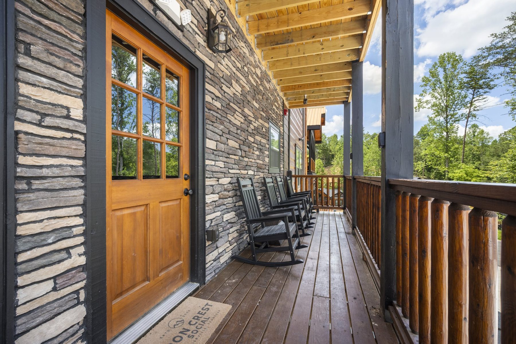 Front porch with a timber door, stone cladding and rocking chairs