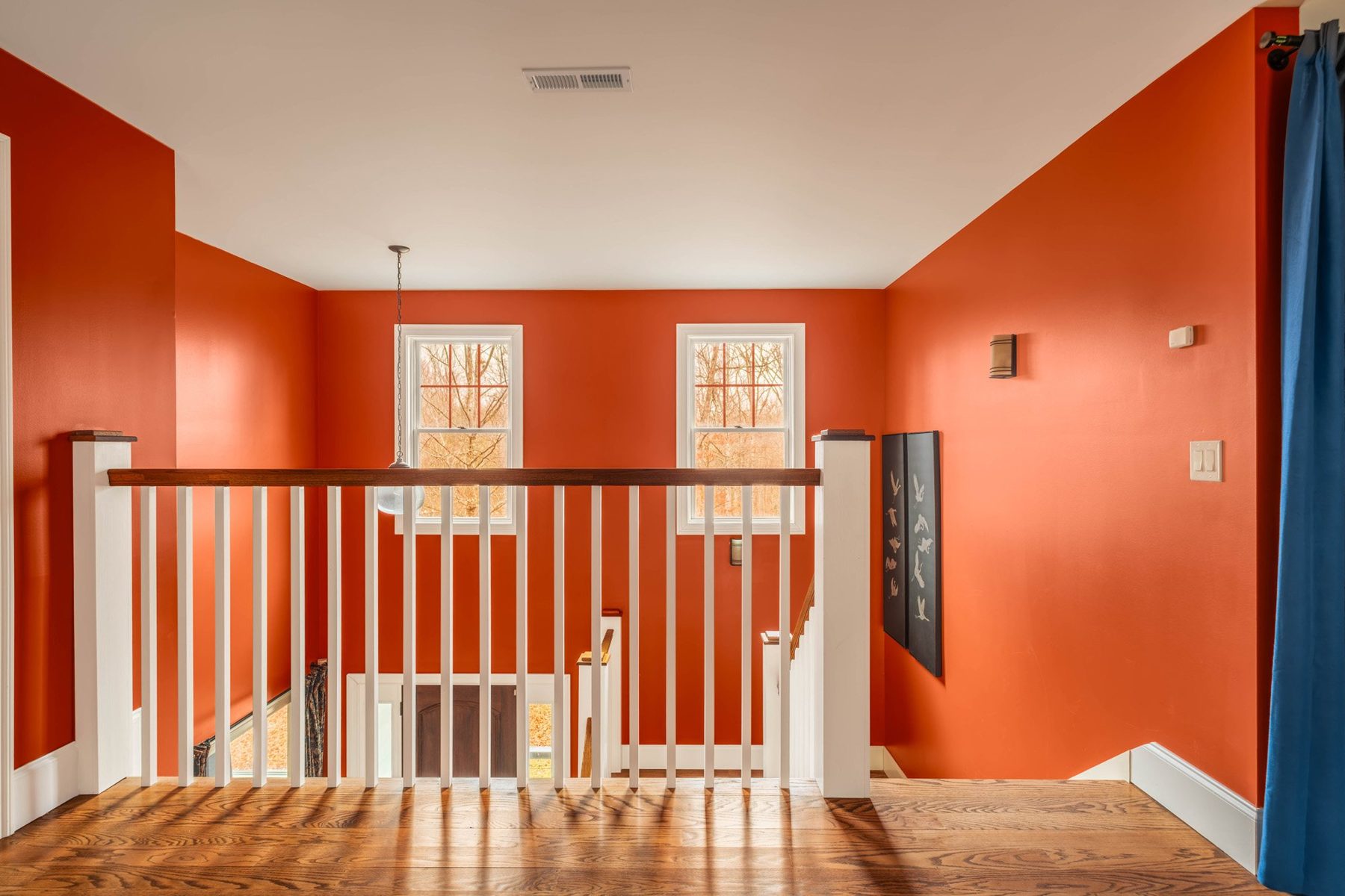 Upper landing in rust red with white balustrade and twin windows
