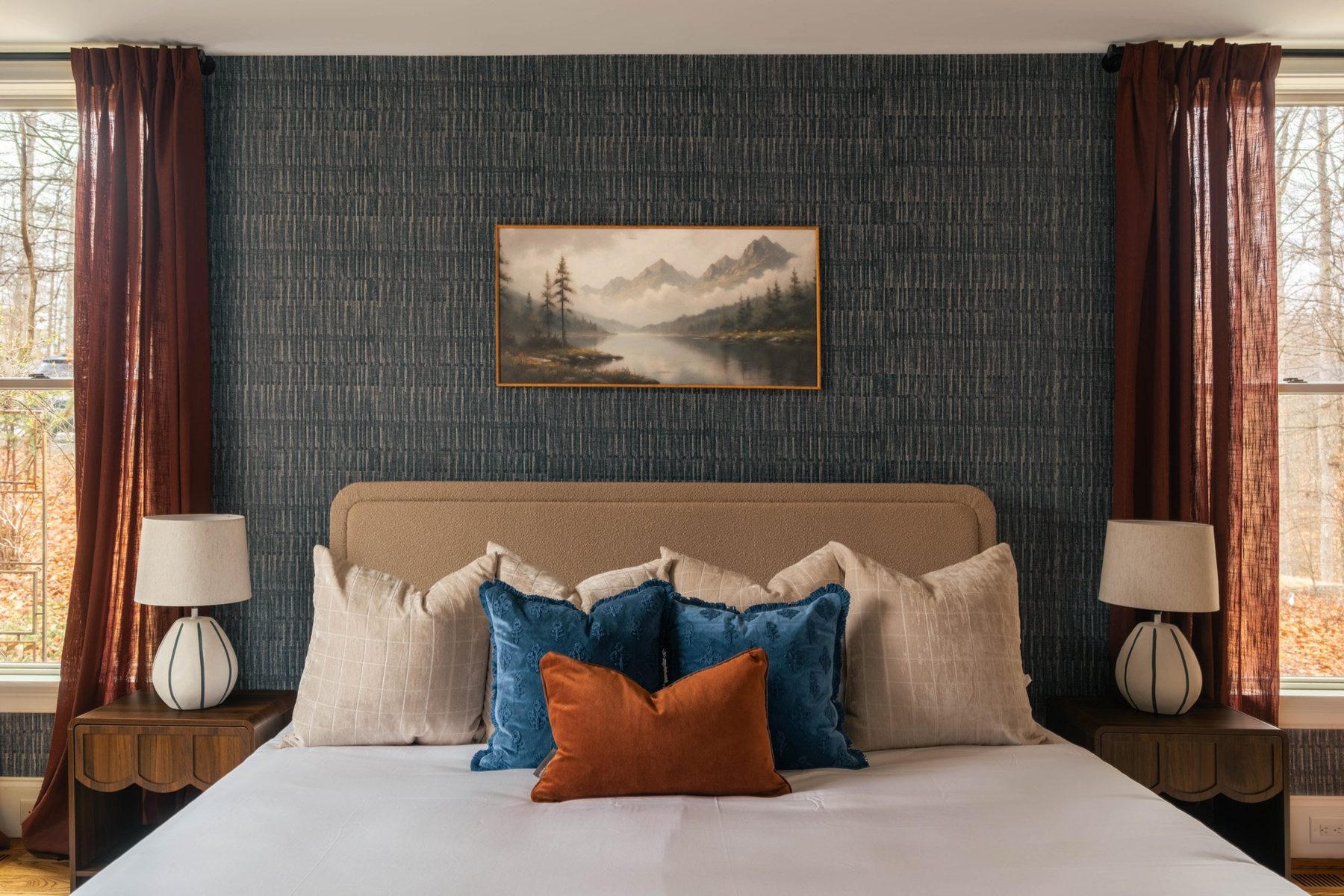 Primary bed against textured navy wallpaper with mountain landscape art
