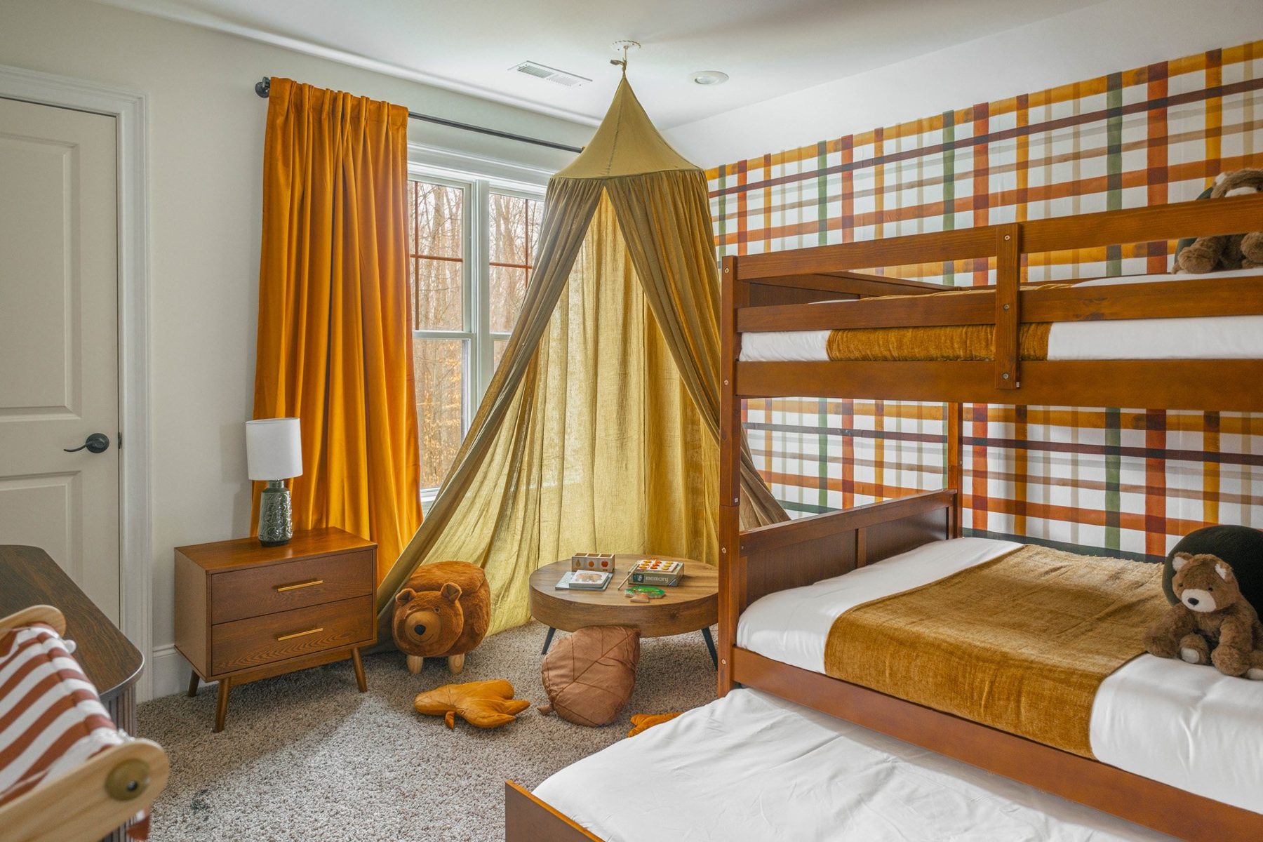 Bunk room with plaid wallpaper, a mustard canopy tent and bear stools