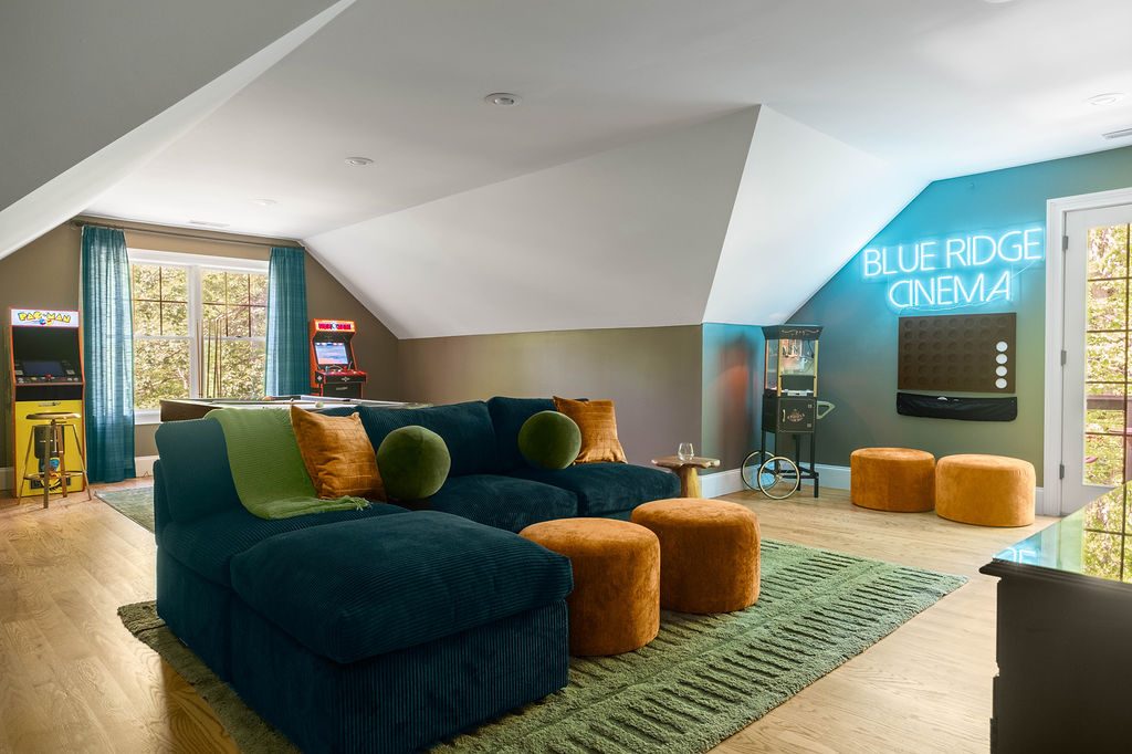 Den with a navy velvet sectional, rust ottomans and a Blue Ridge Cinema neon sign