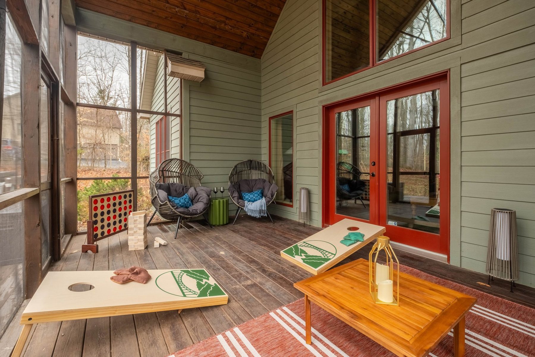 Screened porch with cornhole, egg chairs and a vaulted timber ceiling