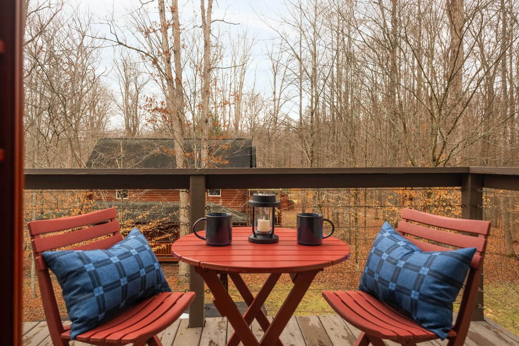 Deck bistro set with blue checked cushions and coffee for two among the trees