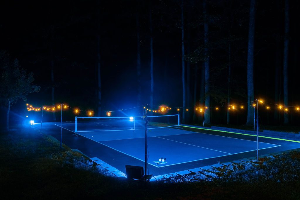 The pickleball court at night under blue lighting and festoon lights