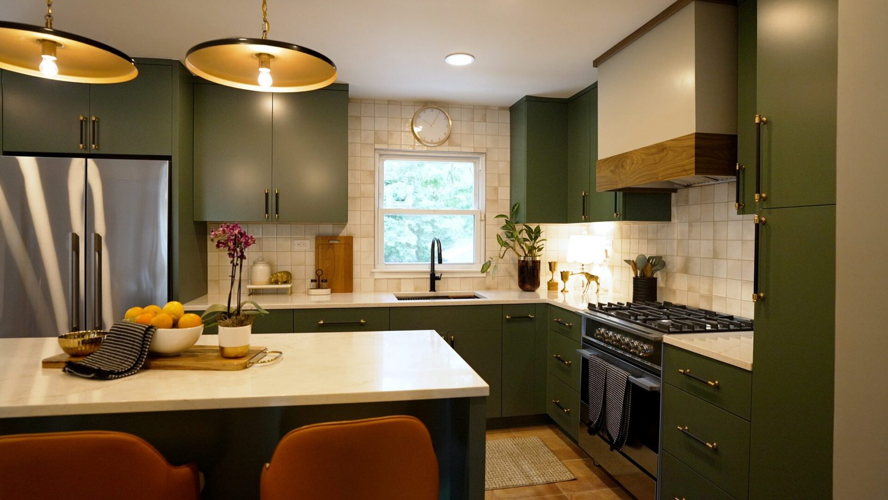 After: the open kitchen with sage green cabinets, island seating and brass pendants