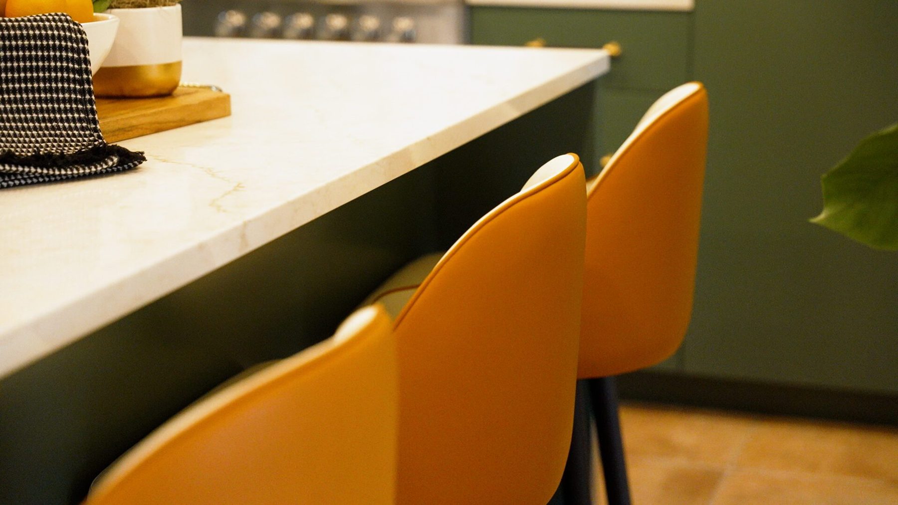 Veined quartz island edge with tan leather counter stools
