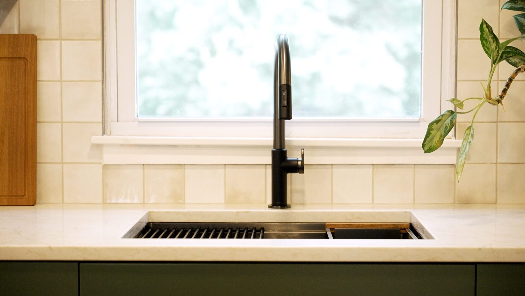 Workstation sink with a matte black tap beneath the window